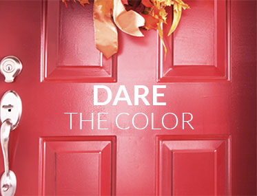 Porte d’entrée rouge vif avec une décoration automnale et le message ‘Osez la couleur’, encourageant l’utilisation de couleurs audacieuses pour les portes.